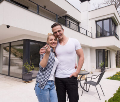 Portrait of a happy young couple hugging in front of their new luxury home villa