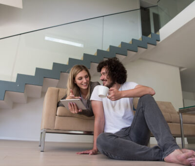 Young couple relaxing at luxurious home with tablet computers reading in the living room on the sofa couch.